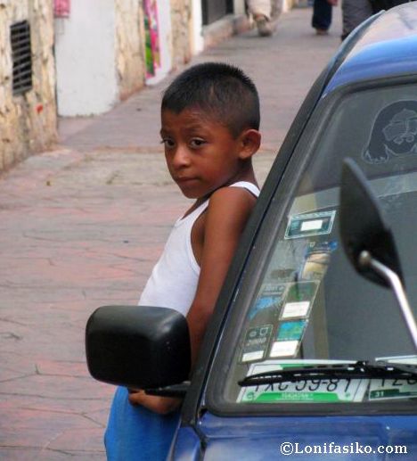 Niño vallisoletano esperando apoyado en coche